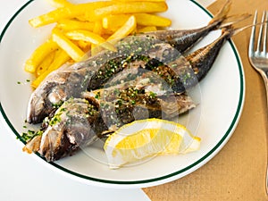 Grilled mackerel fish with french fries and lemon