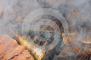 Grilled mackerel fish with smoke on a charcoal barbecue grill