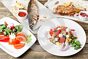 Grilled mackerel and sea bass. Salad of fresh vegetables. Serving on a wooden Board on a rustic table. Barbecue