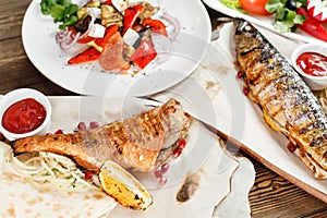 Grilled mackerel and sea bass. Salad of fresh vegetables. Serving on a wooden Board on a rustic table. Barbecue