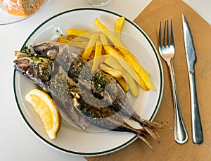 Grilled mackerels with French fries, lemon and sauce