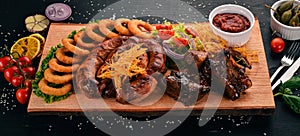 Grilled meat on the board. Sausage, ribs and fresh vegetables. On a wooden table.