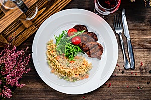 grilled meat and couscous on wood table