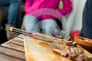 Grilled meat cut into dice, on wooden board, on the table. End o