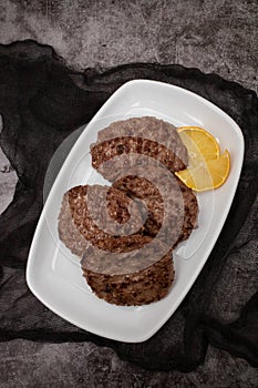 grilled meat cutlets for burger with lemon on white dish