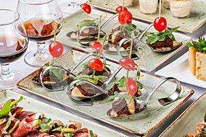 Grilled meat fillet canapes with cheese, tomatoes and greens in spoon on banquet table. Catering food, appetizer platter and