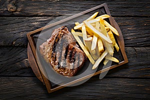 Grilled meat and fries presented enticingly on a wooden table
