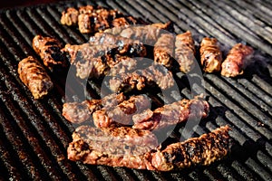 Grilled meat rolls called Mici or Mititei, traditional fresh Romanian bbq grill food cooked on the barbeque at a street food marke