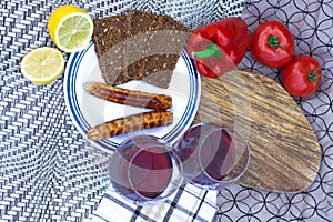 Grilled meat sausages with fresh vegetables. Two glasses of red wine