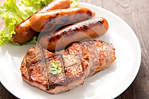 Grilled meat, sausages and vegetables on dish close up