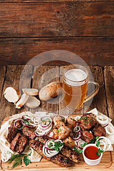 Grilled meat served with beer on rustic table