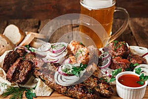 Grilled meat served with mug of cold beer close up