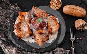 Grilled meat or shish kebab, shashlik on pita bread with tomato sauce on slate board over dark stone background. Top view