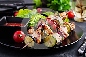 Grilled meat skewers, chicken shish kebab with zucchini, tomatoes and red onions.