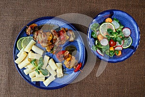 Grilled meat skewers with pasta on plate with vegetable sal