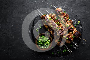 Grilled meat skewers, shish kebab on black background, top view