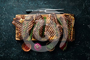 Grilled meat steaks on a wooden board: t-bone, striploin, Rib eye, new york steak.