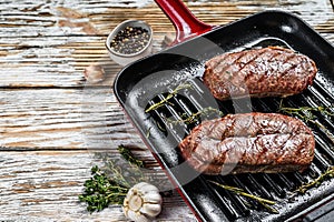 Grilled meat Top Blade steaks in a frying pan. Gray background. Top view. Copy space