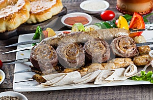 Grilled meat and vegetable kebabs on the white plate