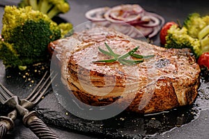 Grilled meat and vegetables. Appetizing pork loin and broccoli on a black stone cutting board. Close-up