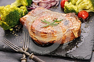 Grilled meat and vegetables. Appetizing pork loin and broccoli on a black stone cutting board. Close-up