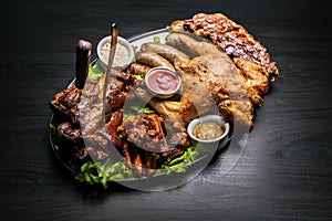 Grilled meat, vegetables, chicken, hot dogs, sausages grilling, sauce, salad served on a plate