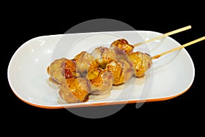 Grilled meatballs or pork on skewers with chili sauce in white plate, focus selective