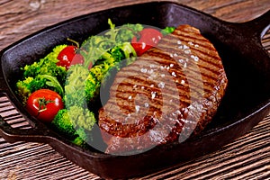 Grilled medium rare beef steak with broccoli and tomato on grill pan