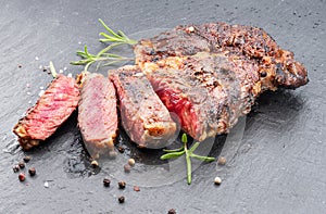 Grilled medium rare ribeye steak on gray stone plate