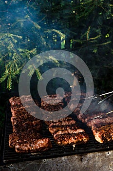 Grilled minced meat rolls called Mici or Mititei in traditional Romanian cuisine cooked outside on a summer day on barbeque grill