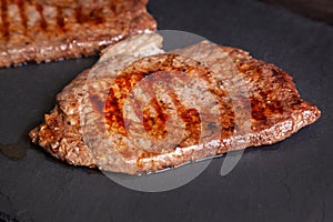 Grilled minute steak of marbled beef on a stone slate board, close up