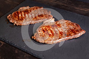 Grilled minute steak of marbled beef on a stone slate board, close up