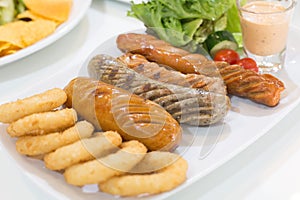 Grilled mixed sausages on white plate on the dining table in restaurant