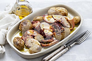 Grilled octopus with potato, olive oil on white dish on ceramic background