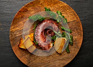 Grilled octopus tentacle on a wooden plate served with shrimps