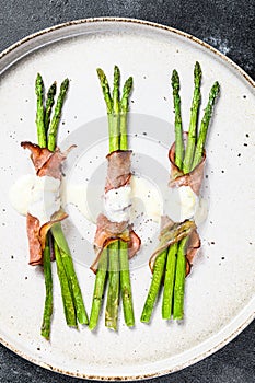 Grilled organic asparagus wrapped in pork bacon. Black background. Top view