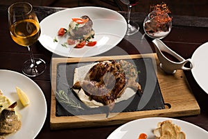 Grilled partridge, sea bass, Tartarus. Different dishes on the table in the restaurant.