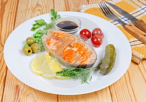 Grilled piece of arctic char with vegetables, fork and knife