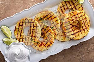 Grilled pineapple served with fresh lime wedges and whipped cream