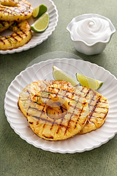 Grilled pineapple served with fresh lime wedges and whipped cream