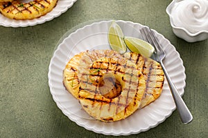 Grilled pineapple served with fresh lime wedges and whipped cream