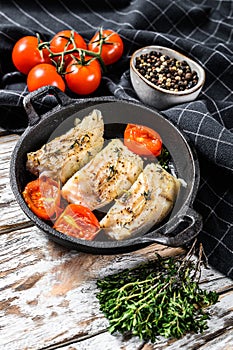 Grilled pollock or coalfish fillets in a pan. White background. Top view