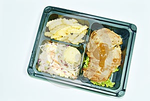 Grilled pork black pepper steak dressing gravy sauce with mashed potato and salad dipping chili sauce on plastic packaging