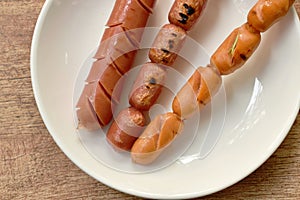 Grilled pork and chicken sausage stabbing in wooden stick on plate