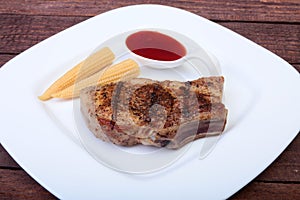 Grilled pork chop with Cranberry sauce and Mini Corn cob preserved on plate on wooden board