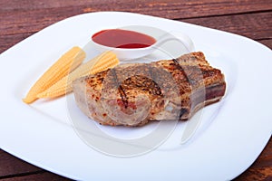 Grilled pork chop with Cranberry sauce and Mini Corn cob preserved on plate on wooden board