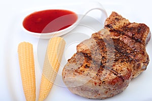 Grilled pork chop with Cranberry sauce and Mini Corn cob preserved on plate on wooden board