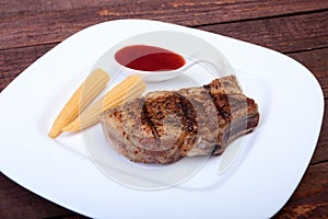 Grilled pork chop with Cranberry sauce and Mini Corn cob preserved on plate on wooden board