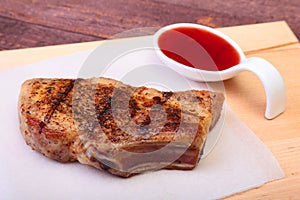 Grilled pork chop with Cranberry sauce on plate on wooden board