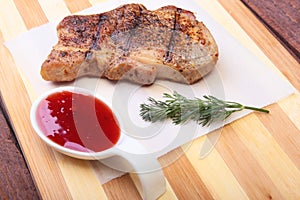 Grilled pork chop with Cranberry sauce on plate on wooden board